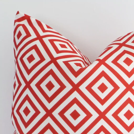 Close up image of outdoor square cushion. The image allows you to see the red hue and geometric style more thoroughly.