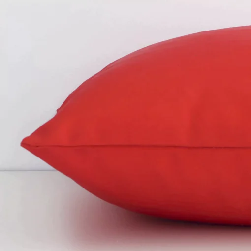 Side edge of solid-coloured cushion. The outdoor material and red colour can be seen from this lateral viewpoint.
