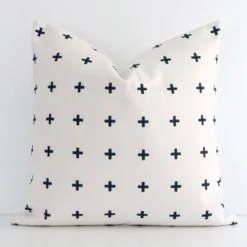 A white wall that has a black patterned cushion cover positioned in front of it. It has an exquisite linen material and a lovely square shape.