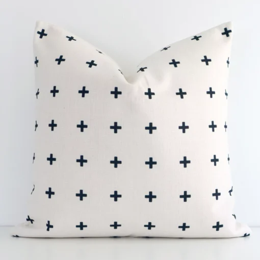 A white wall that has a black patterned cushion cover positioned in front of it. It has an exquisite linen material and a lovely square shape.