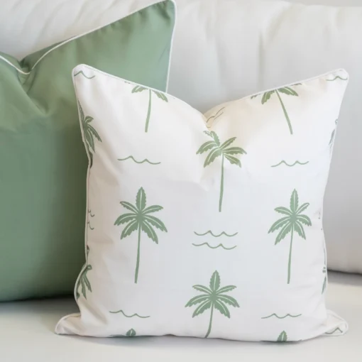 Tropica green cushions with palm print paired with solid sage cushion on sofa.