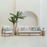 Wildgrove frond outdoor cushions styled on sofa and chair with palm nearby.