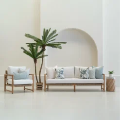 Wildgrove frond outdoor cushions styled on sofa and chair with palm nearby.
